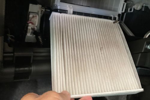 車のエアコンフィルターを交換している作業の写真