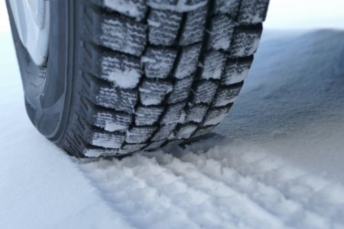 ゴムが柔らかいスタッドレスタイヤで雪道を走行している画像
